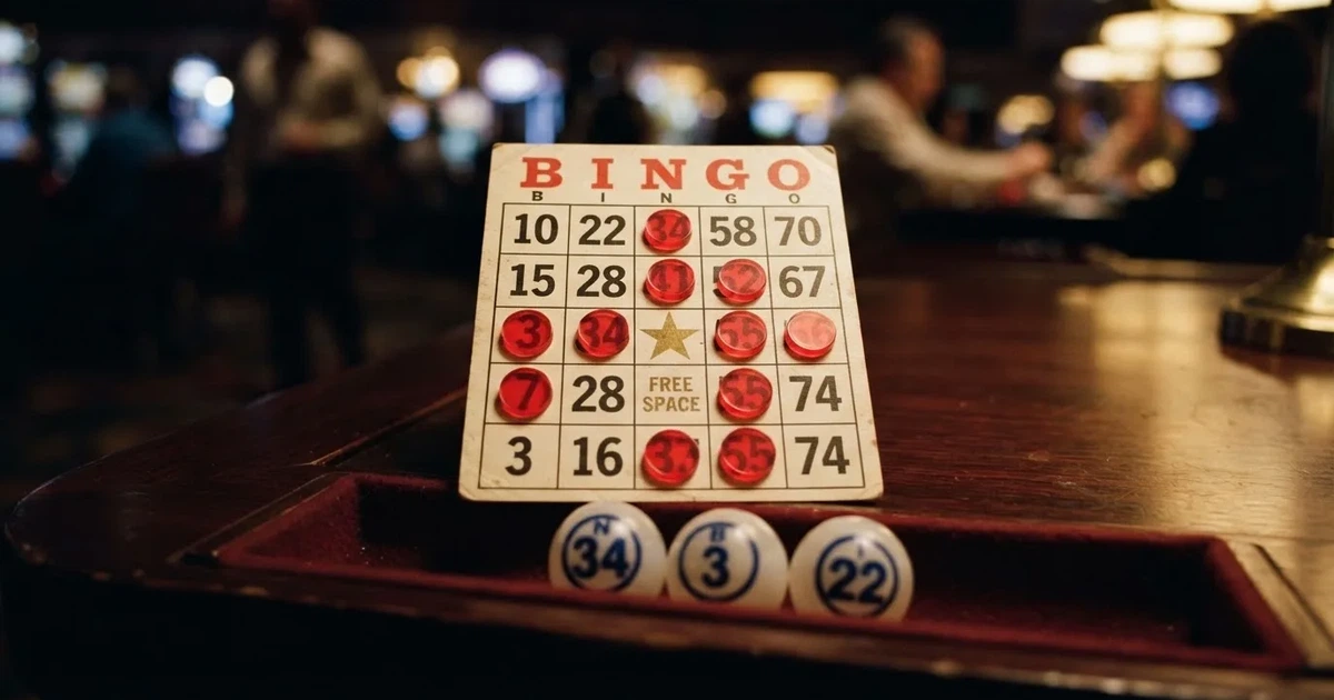 Karta do bingo z odznaczonymi liczbami obok wylosowanych kulek na stole w kasynie online